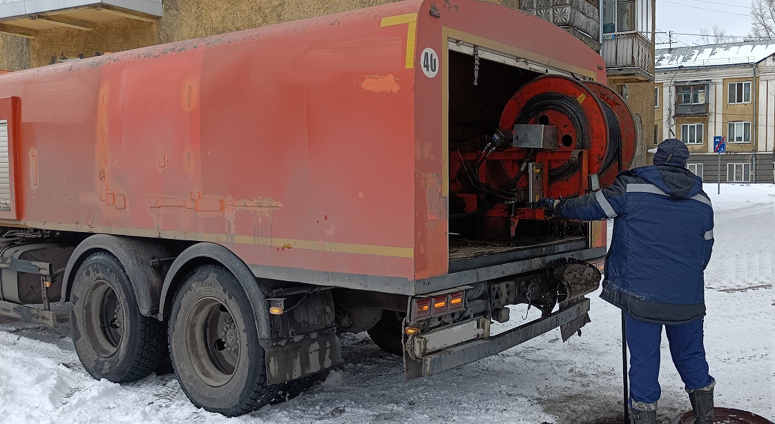 Каналопромывочная машина и работник прочищают засор в канализационной системе в Нефтеюганске